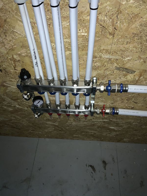 Manifold with flow and return pipes fixed to an unfinished timber wall